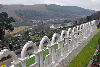 Aberfan Cemetery. The line of white arches mark the graves of the children killed in the colliery tip disaster in 1966.<br>Photo: Stephen McKay, Geograph Project, cc-by-sa/2.0